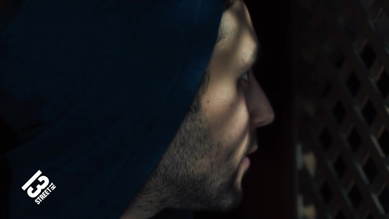 A priest in profile in a dark confessional.